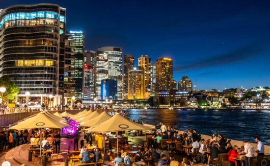 Sydney, Australia - 10 2018: People eating and drinking outside the Opera House at dusk, with a breathtaking view over Harbour Bridge and Circular Quay. High quality photo